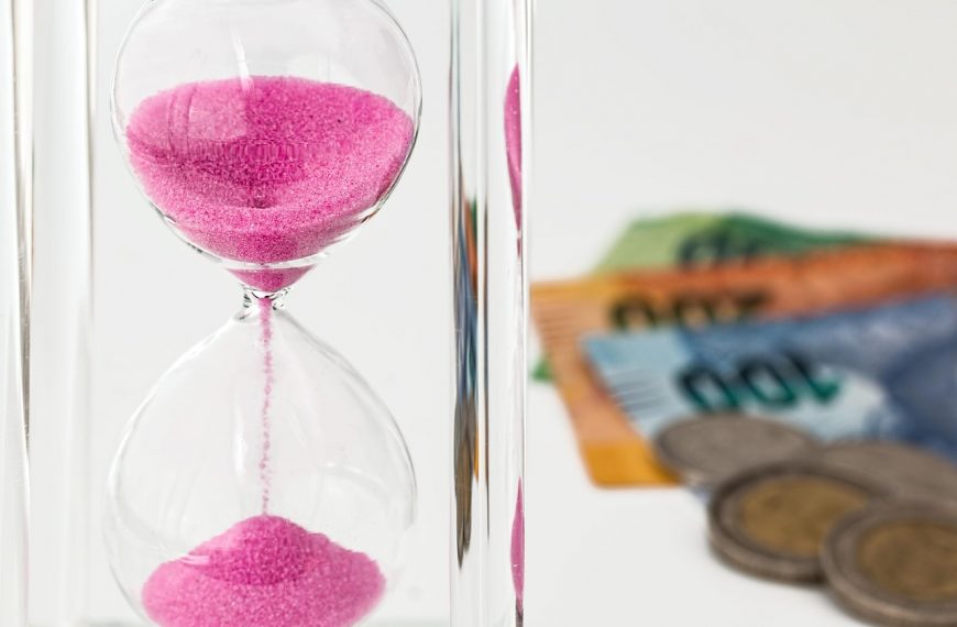 hourglass with pink sand, coins, and banknotes