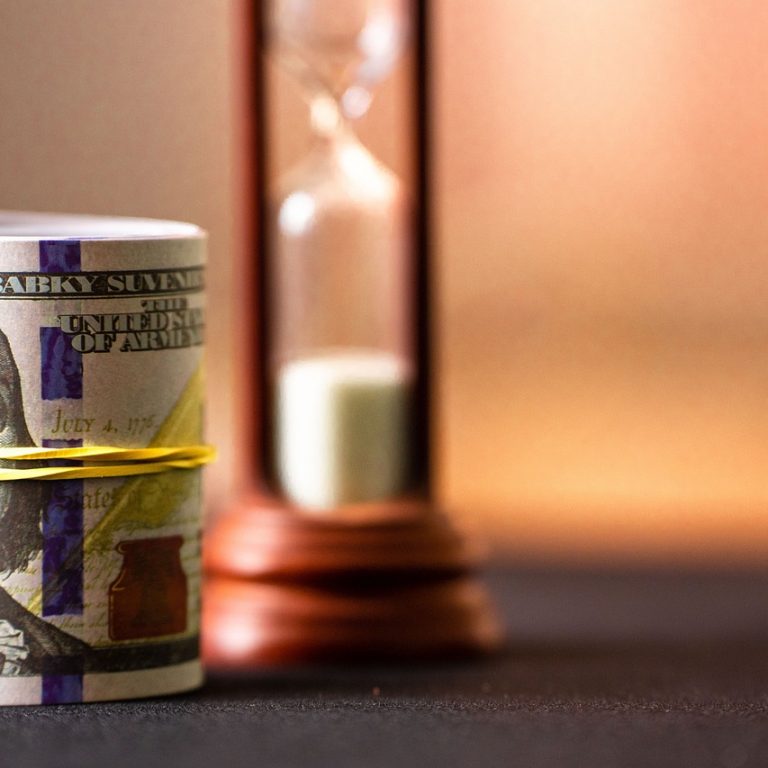bundle of cash and an hourglass behind it
